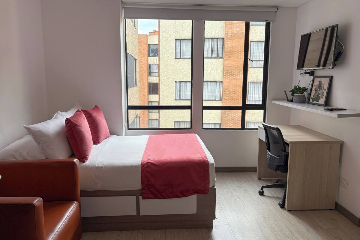 Een moderne slaapkamer met een bed, een bureau en een televisie.