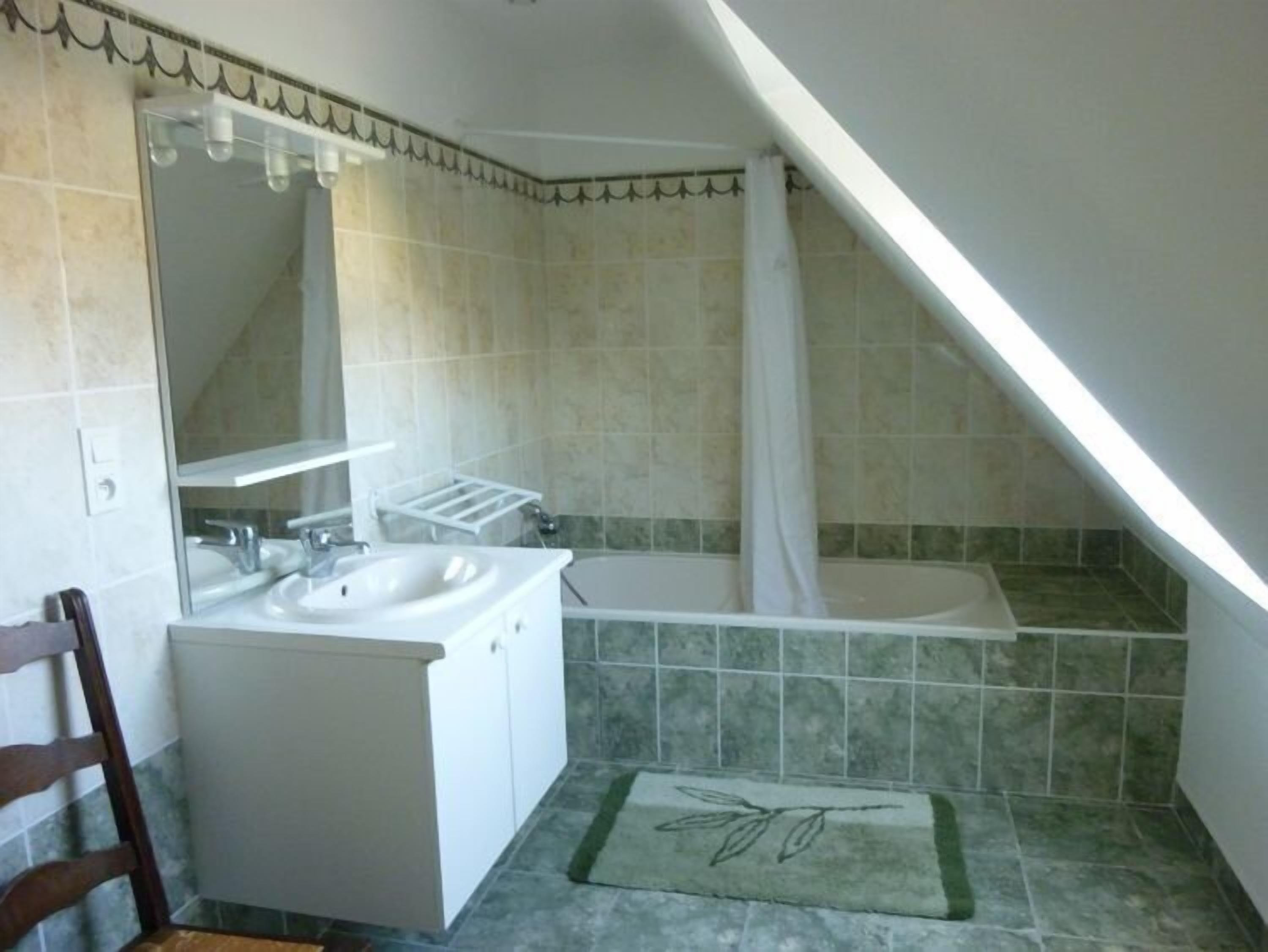 A bathroom with a sink, mirror, and bathtub.