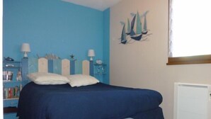A bedroom with a bed, bedside tables, a nightstand, a window with blinds, and a wall painting. - Sea and shops on foot, T2 ground floor for 4 people. (DAMGAN)