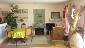 Un comedor con una mesa preparada para cuatro personas, una chimenea y una decoración de gran tronco de árbol.