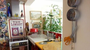 Una cocina con estufa antigua, tabla de cortar de madera y horno empotrado.