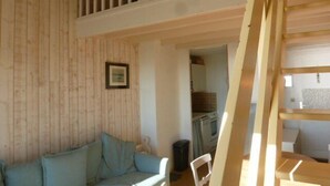 Ein Zimmer mit einer Holzwand, einem blauen Sofa, einem weißen Stuhl und einer Treppe.