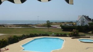 Ein Poolbereich mit Blick auf das Meer und ein Haus im Hintergrund.