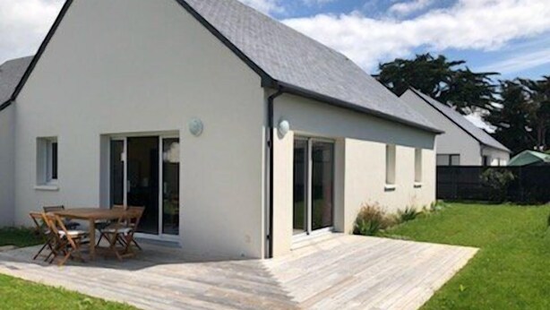 Une maison moderne dotée d’un patio, d’un coin repas et d’une grande porte-fenêtre coulissante.