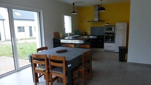 Une cuisine moderne avec un coin repas, de grandes fenêtres et une vue sur l’extérieur.