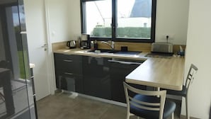 A compact kitchen with a sink, a coffee maker, and a window above the counter. - Maison 8 personnes, la mer et la campagne (AMBON)