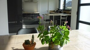 A modern kitchen with a dining table, chairs, and a potted plant. - Maison 8 personnes, la mer et la campagne (AMBON)