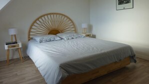 A bedroom with a wooden headboard, a bed with white bedding, two bedside tables with lamps, and a framed picture on the wall. - Maison 8 personnes, la mer et la campagne (AMBON)