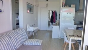Ett kompakt bostadsutrymme med en soffa, ett matbord, ett litet kök och en liten hall.