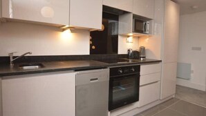 A modern kitchen with white cabinets, a stainless steel sink, a built-in microwave, and a dishwasher. - Home from home in style & comfort (Chester)