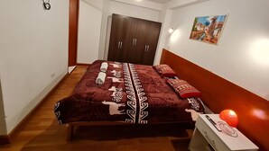 Ein Schlafzimmer mit Bett, Kleiderschrank, Fernseher und einem Bild an der Wand.