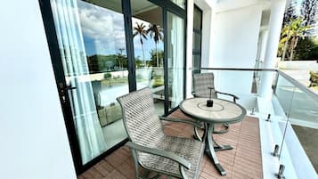 A balcony with a glass door, two wicker chairs, and a round table.