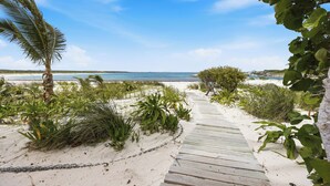 A wooden pathway leading to a beach with palm trees and shrubs. - Waterfront House located in Schooner Bay, Abaco (Crossing Rocks)