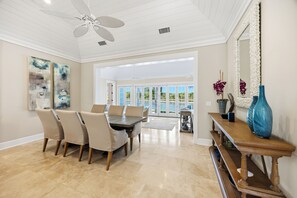 A dining area with a table and chairs, a ceiling fan, and a view through glass doors to an outdoor space.