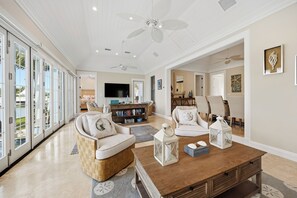 A spacious living room with a large TV, comfortable seating, and a view of the outdoors.