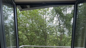 A balcony with a wooden table and chairs, overlooking a forested area. - Remarkable 2-bed Apartment in Leeds (Leeds)