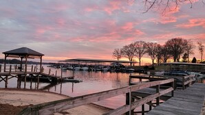 A marina with wooden docks and a gazebo, boats docked, and a sunset sky.