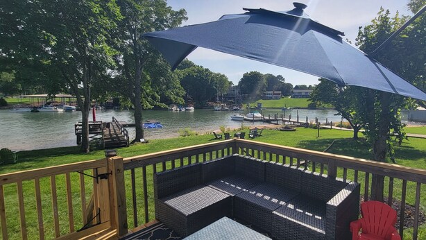 A deck with a view of a lake, docked boats, and a grassy area.