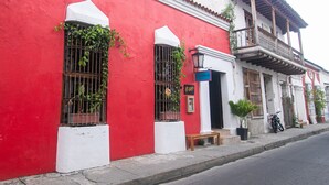 A red building with white trim, a balcony, and a bench outside. - Casa Be Getsemani (Cartagena)