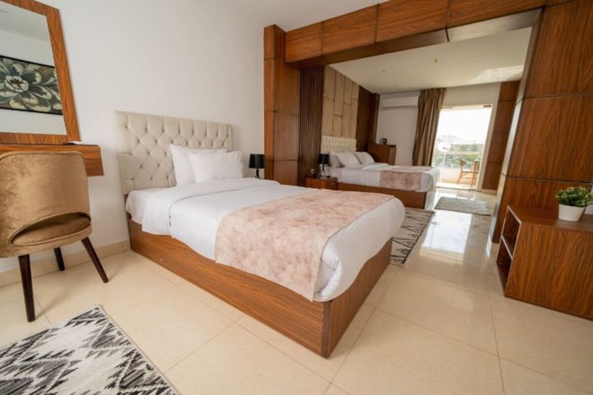Un dormitorio moderno con una cama grande, una silla, un escritorio y un espejo.