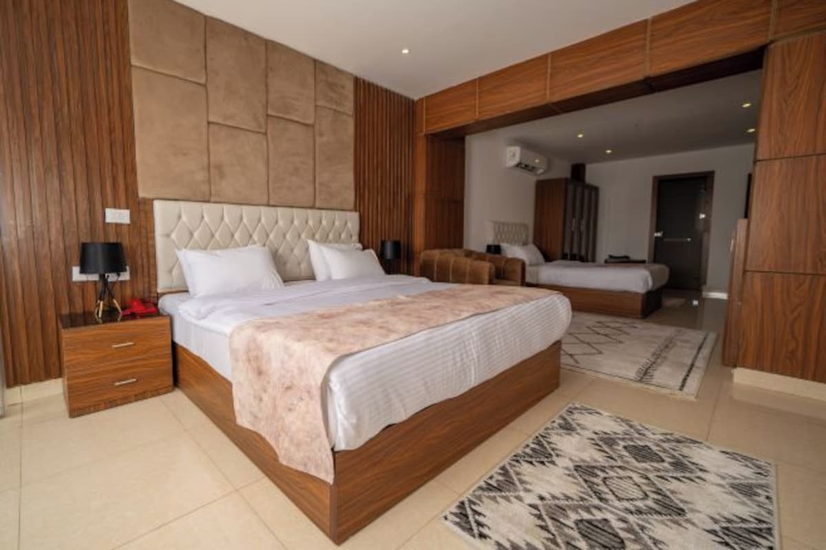 Ein modernes Schlafzimmer mit einem großen Bett, Holzvertäfelung und einem gemusterten Teppich.