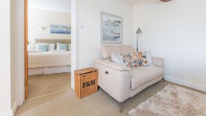 A cozy living room with a beige sofa, a wicker basket, and a framed picture on the wall. - Beautiful 4* Cottage in a peaceful, rural setting with Country Club membership.  (Saltash)