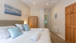 A hotel room with a bed, a painting, a wardrobe, and a door. - Beautiful 4* Cottage in a peaceful, rural setting with Country Club membership.  (Saltash)