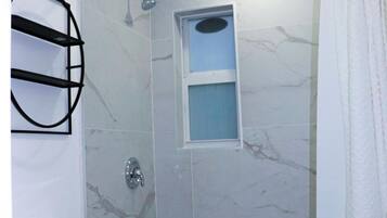 Une salle de bain avec une douche, des toilettes et une petite fenêtre.