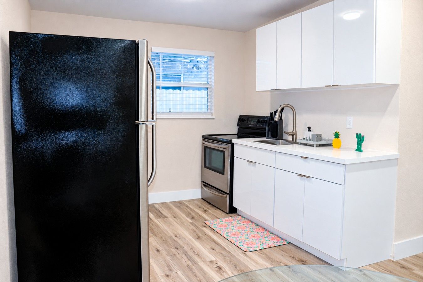 A compact kitchen with a black refrigerator, a stove, and a sink.