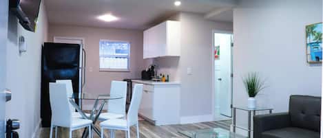 Una sala moderna con una mesa de centro de vidrio, un sofá y un comedor con una mesa y sillas de vidrio.