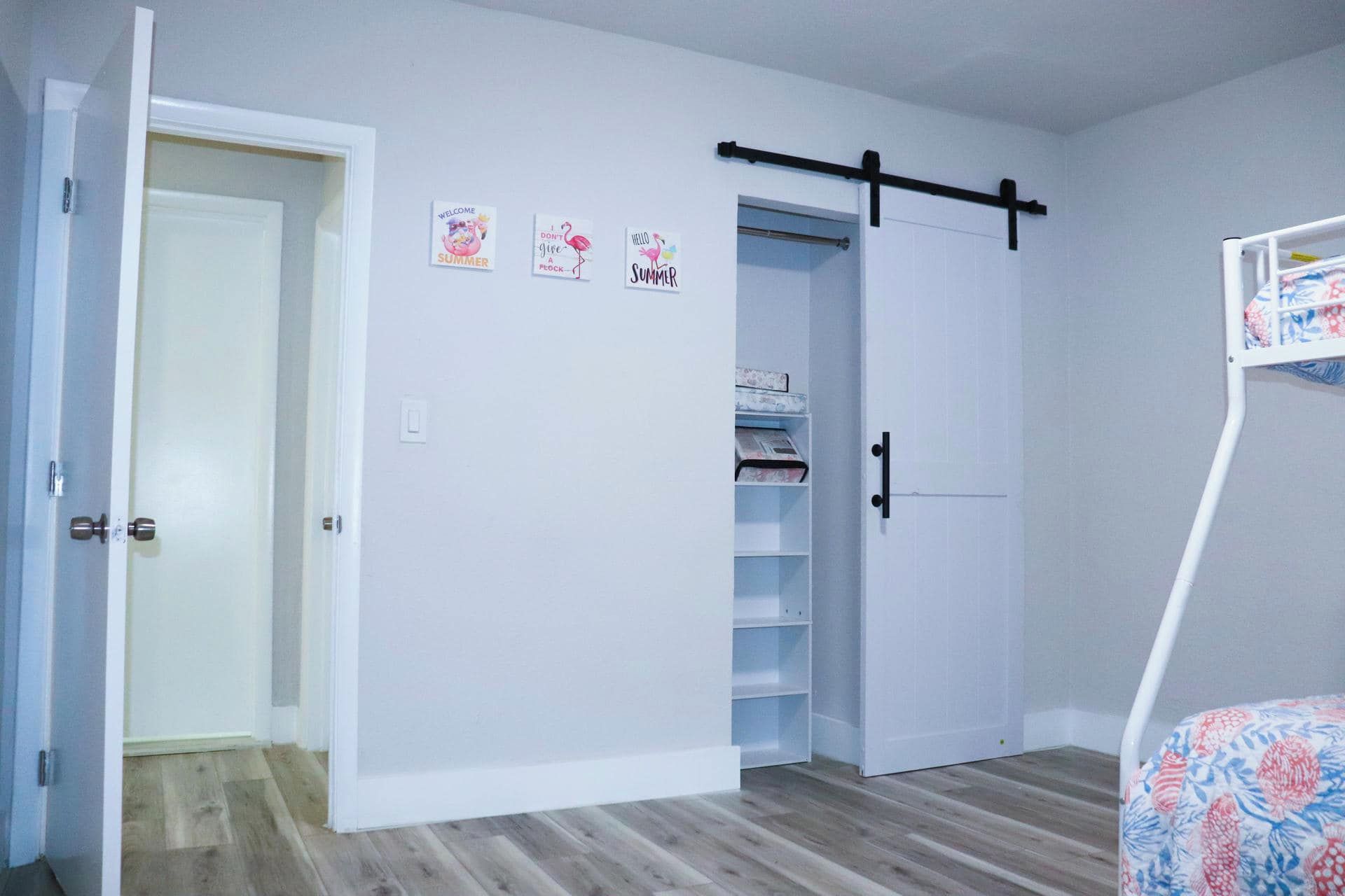 A room with a white door, a closet with shelves, and a bed with a floral bedspread.