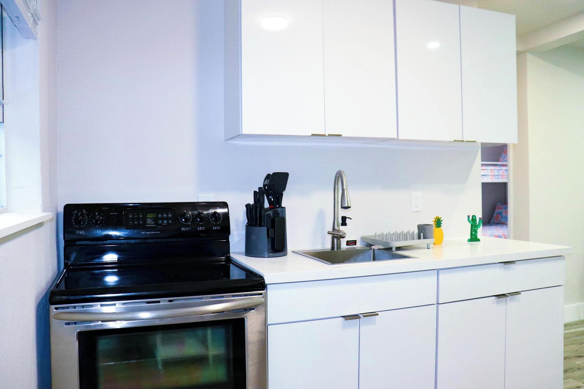 Una cocina moderna con armarios blancos, estufa de acero inoxidable y un lavamanos.