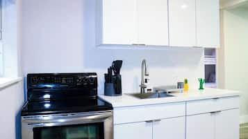 Una cocina moderna con armarios blancos, estufa de acero inoxidable y un lavamanos.