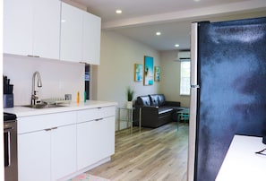 A modern kitchen with white cabinets, a stainless steel sink, and a black refrigerator.