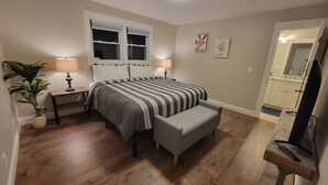 Een slaapkamer met een bed, nachtkastjes, een lamp, een kamerplant en een spiegel.