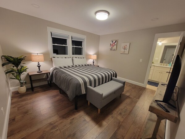 A bedroom with a bed, bedside tables, a lamp, a potted plant, and a mirror.