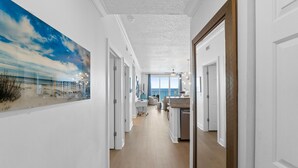 Ein Flur mit einem großen Meeresraumbild, einer Küchenzeile und Blick zum Wohnzimmer.