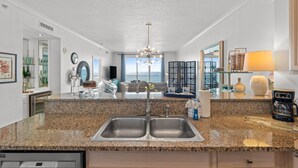 Una cucina moderna con piani in granito, lavelli in acciaio inossidabile e lavastoviglie integrata.