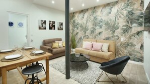 Una sala moderna con un sofá, una mesa de comedor para dos personas y una mesa de centro.