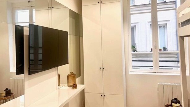 A modern bathroom with a large mirror, white cabinets, and a window providing natural light. - Studio Annah - Studio Apartment, Sleeps 3 (Paris)