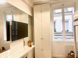 Un baño moderno con un espejo grande, muebles blancos y un ventanal que proporciona luz natural.
