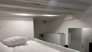 A bedroom with a single bed, a white headboard, and a mirror on the wall. - Studio Annah - Studio Apartment, Sleeps 3 (Paris)