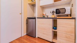 Eine kleine Küche mit Kühlschrank, Mikrowelle und Holzschränken.