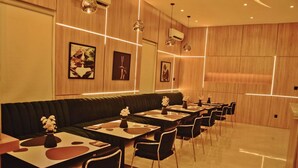 A modern restaurant with wooden panel walls, recessed lighting, and a long black sofa. - El Castillo Pretigious Hotel (Lekki)