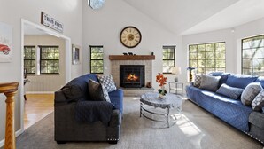 A living room with two sofas, a fireplace, and a clock on the wall.