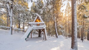 A snow-covered wooden cabin in a forest.