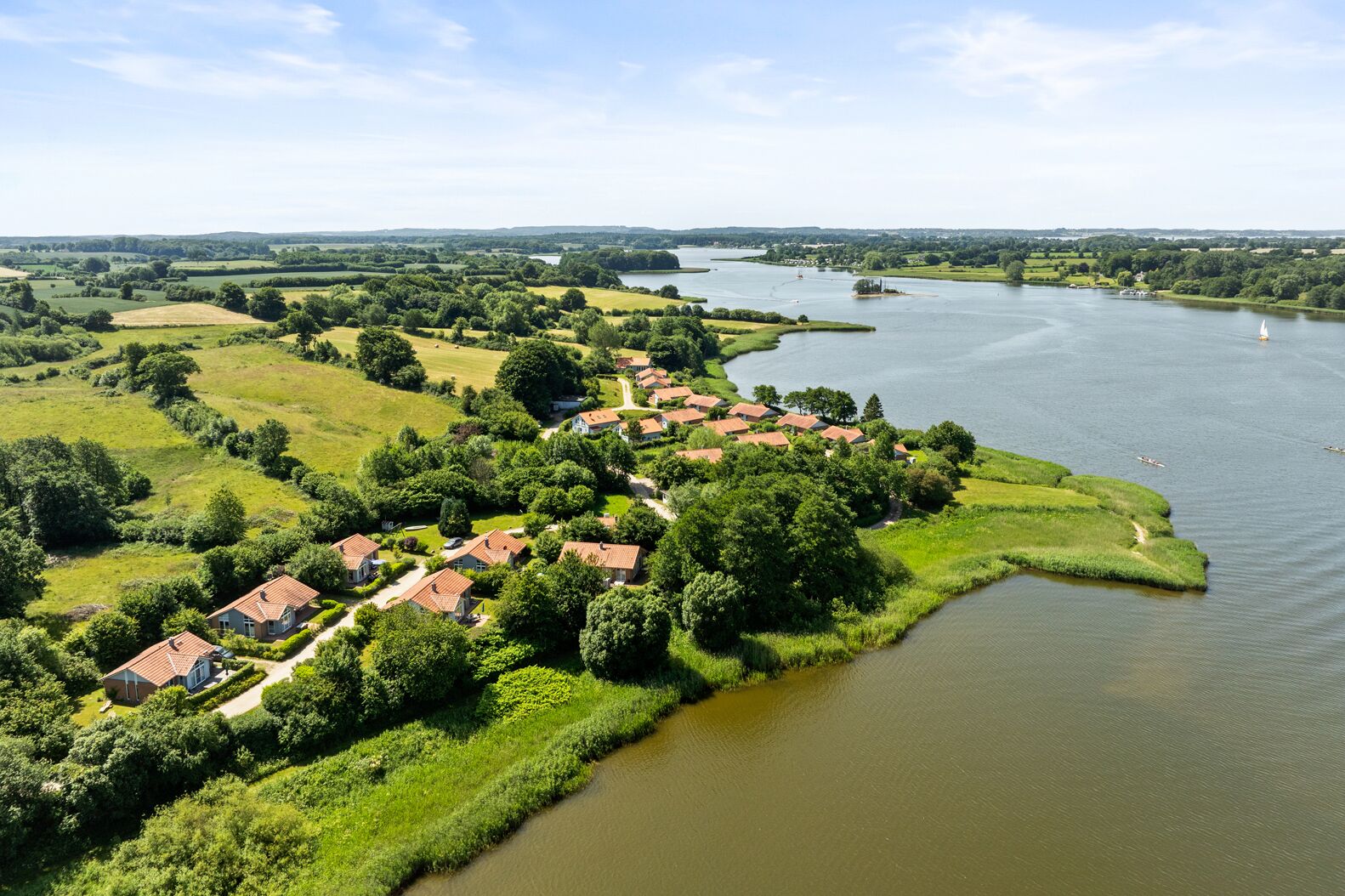 Un villaggio lungo il fiume, con case che costeggiano l'acqua, circondato da vegetazione lussureggiante.