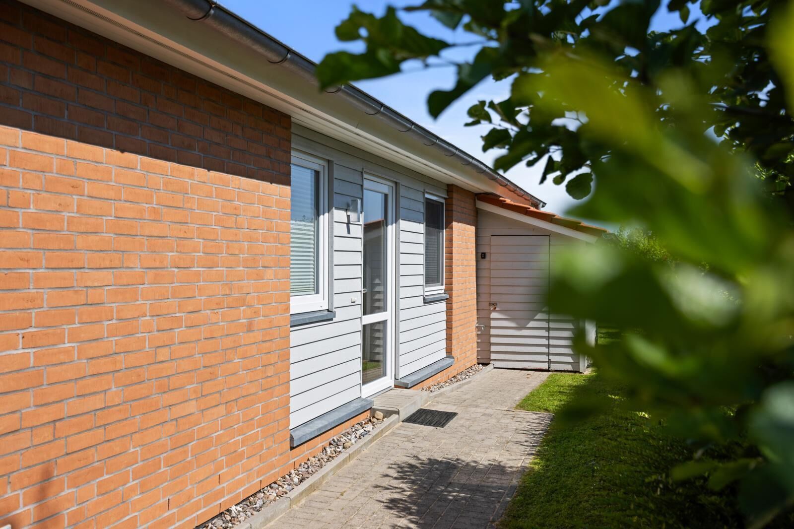 Une maison à deux étages, construite en briques, dotée d’un patio couvert et d’un garage.