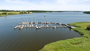 Un puerto deportivo con barcos amarrados, rodeado de vegetación y un lago tranquilo.