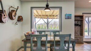 A dining area with a wooden table and chairs, a window with a view of trees, and a hanging light fixture. - Pets welcomed, fully fenced in yard. Beautiful 1BR suite w full kitchen, WI-FI  (Candler)